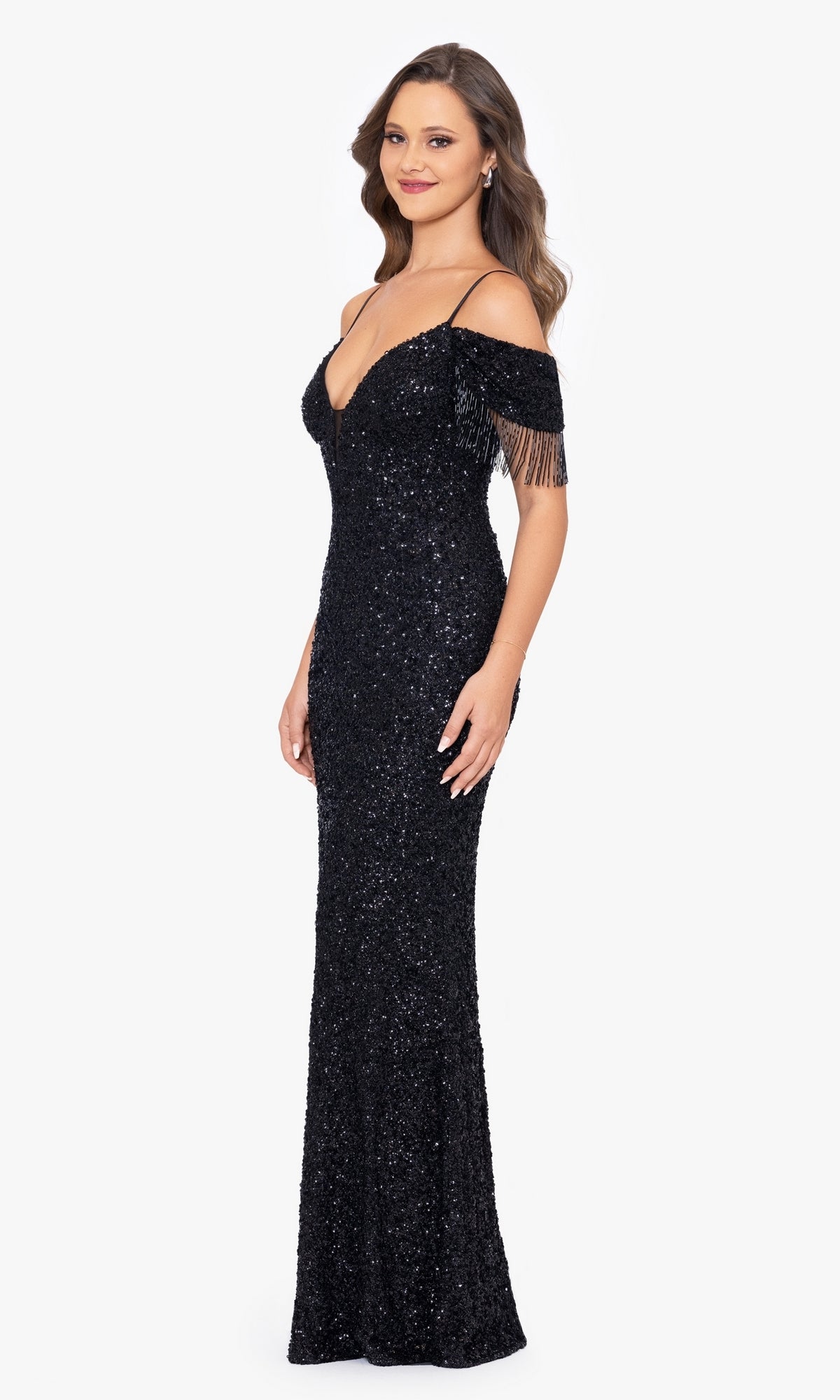 A woman models the Fringed Long Black Beaded Prom Dress A26115, a floor-length cold-shoulder gown with black sequins and fringe sleeves, against a plain white background.